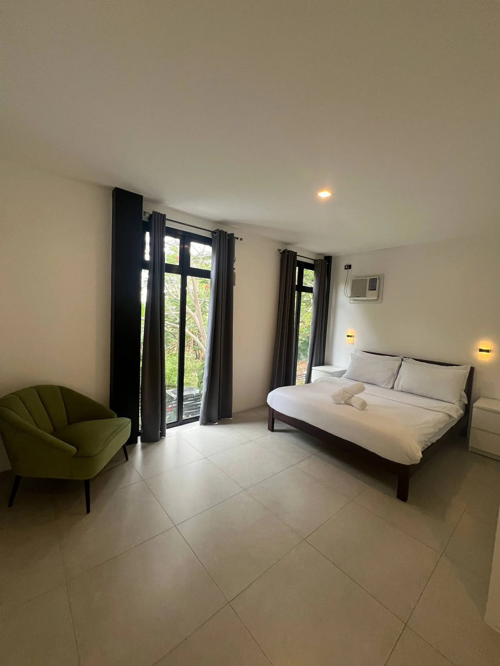 Bedroom 2 with lime-green armchair and garden view through glass windows
