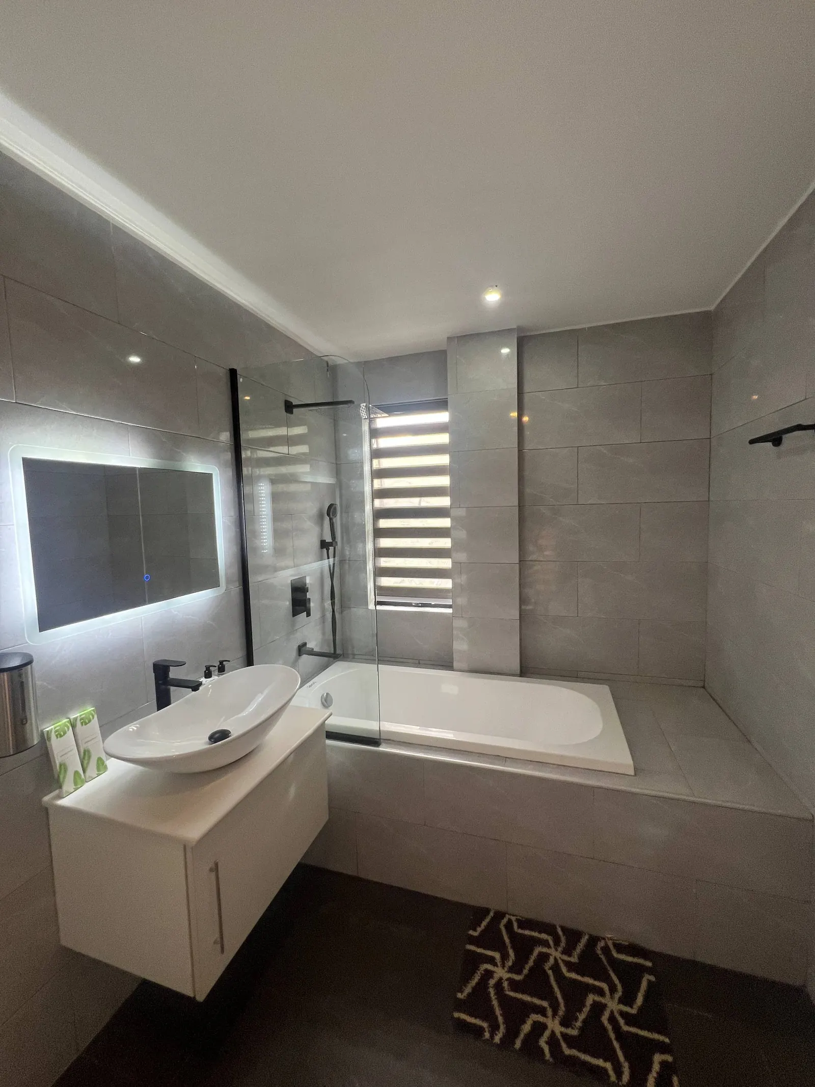 En-suite bathtub with rain shower and window blinds