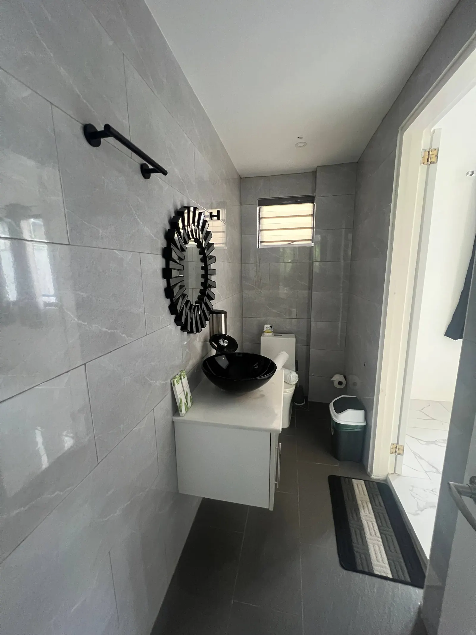 En-suite powder room with sunburst mirror, black sink and vanity