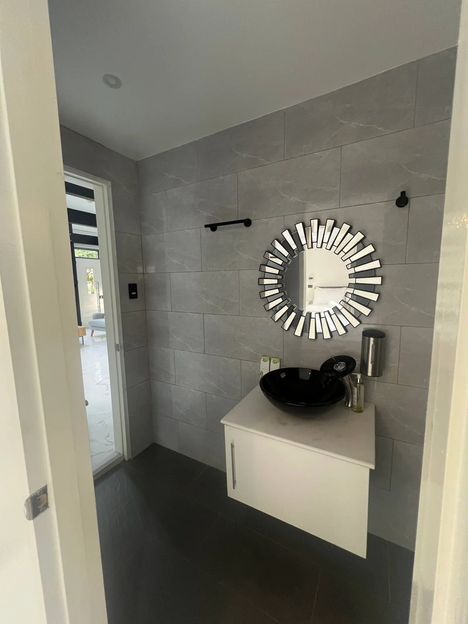 En-suite vanity, round mirror and open door to bedroom