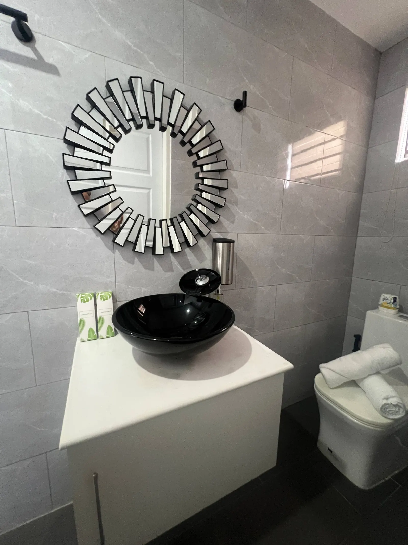 En-suite black vessel sink, sunburst mirror and toilet
