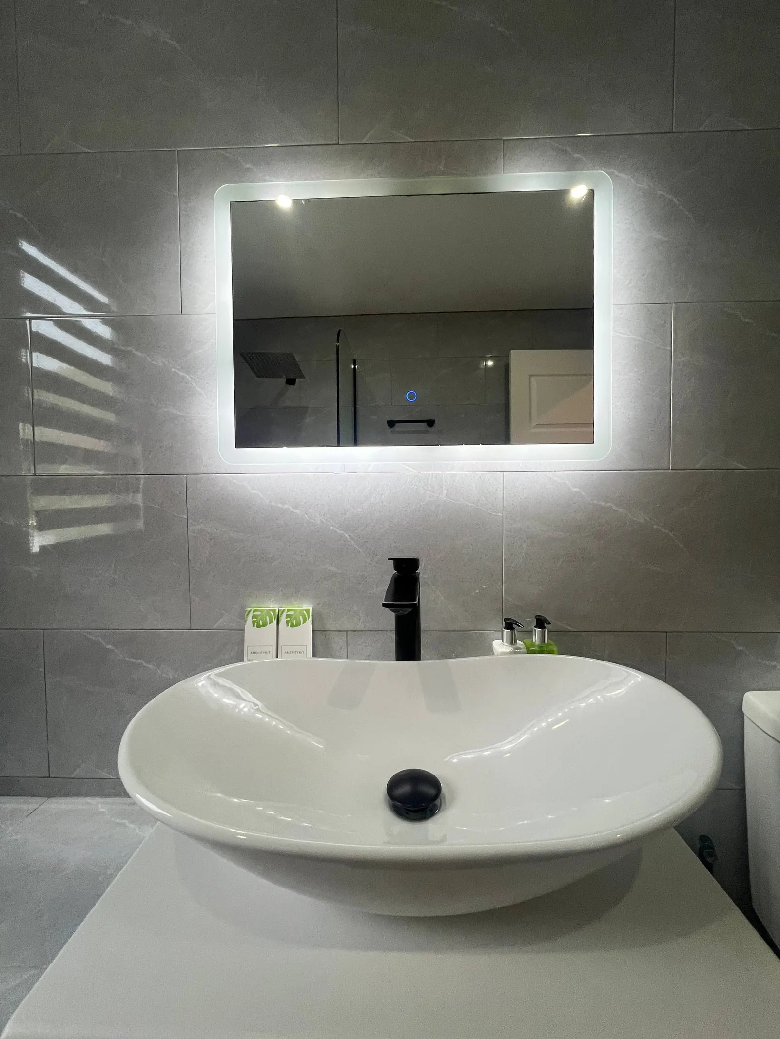 En-suite vanity with backlit mirror and vessel sink