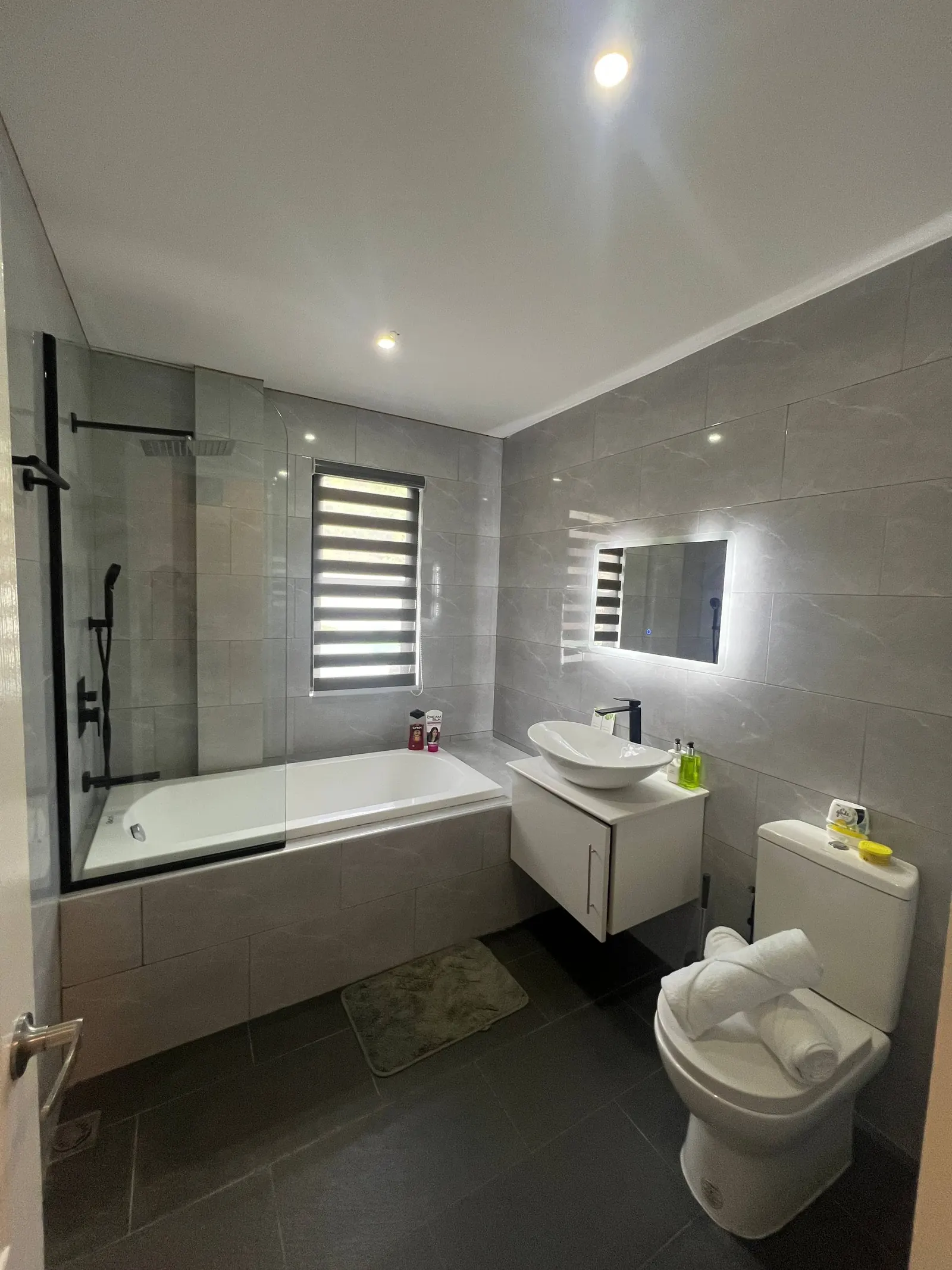 En-suite bathtub with rainfall shower and vanity