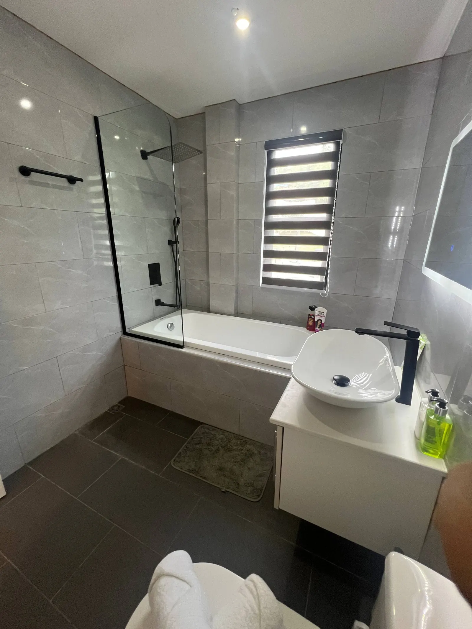 En-suite bathtub with zebra blinds and rainfall shower